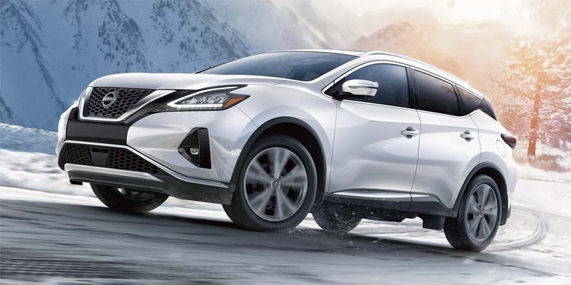 a white 2024 nissan murano driving uphill on a snowy road