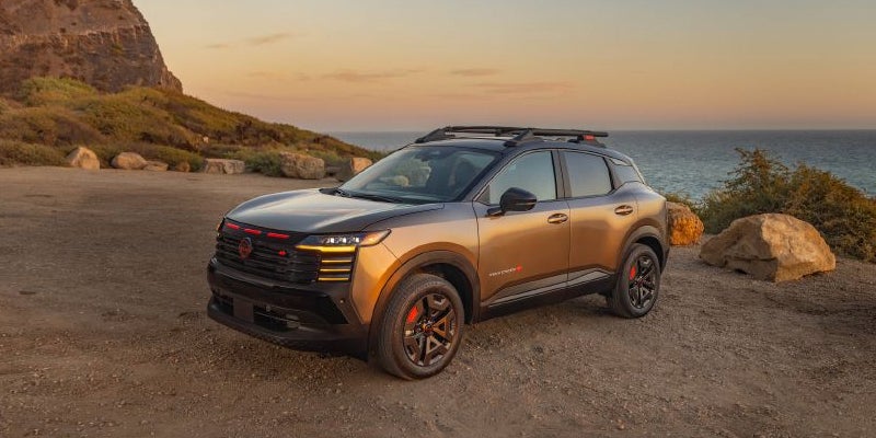 Gray 2027 Kicks parked near the coastline at sunset with a scenic ocean backdrop